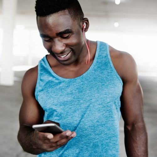 man smiling while looking at his phone during a workout